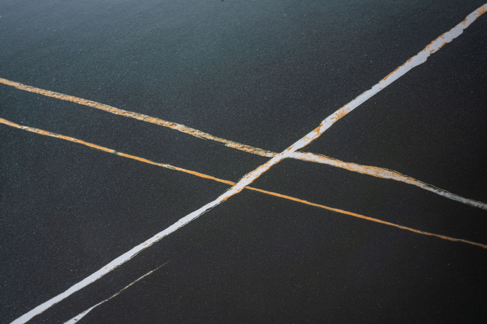 Nahaufnahme einer Tischplatte mit dunkler Oberfläche und hellen, diagonalen Linien.