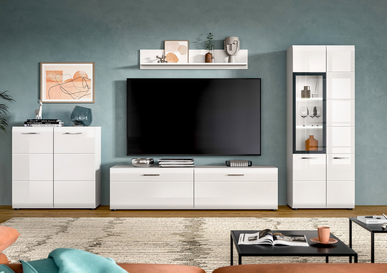 Frontale Ansicht einer modernen weißen Wohnwand im Wohnzimmer mit Lowboard und großem Flachbild-TV, Hängeregal, Sideboard links und Vitrine rechts vor graublauer Wand