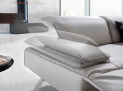 Nahaufnahme einer modernen Eckgarnitur mit verstellbarer Kopfstütze in einem hellen Raum.