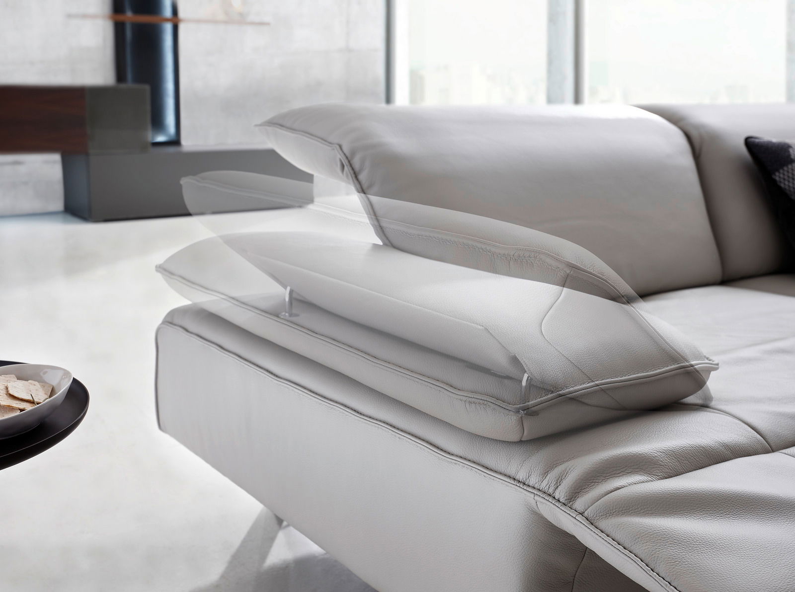 Nahaufnahme einer modernen Eckgarnitur mit verstellbarer Kopfstütze in einem hellen Raum.