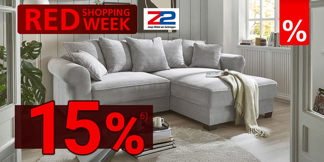 Helles Wohnzimmer mit grauem Ecksofa, Rundteppich, Wandbildern, Tageslicht und rotem „Red Shopping Week“-Banner