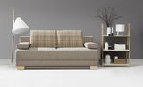 Frontale Ansicht eines modernen Querschläfer-Sofas in Beige mit karierten Rückenkissen, flankiert von einer Stehlampe und einem Regal mit Dekorationen.