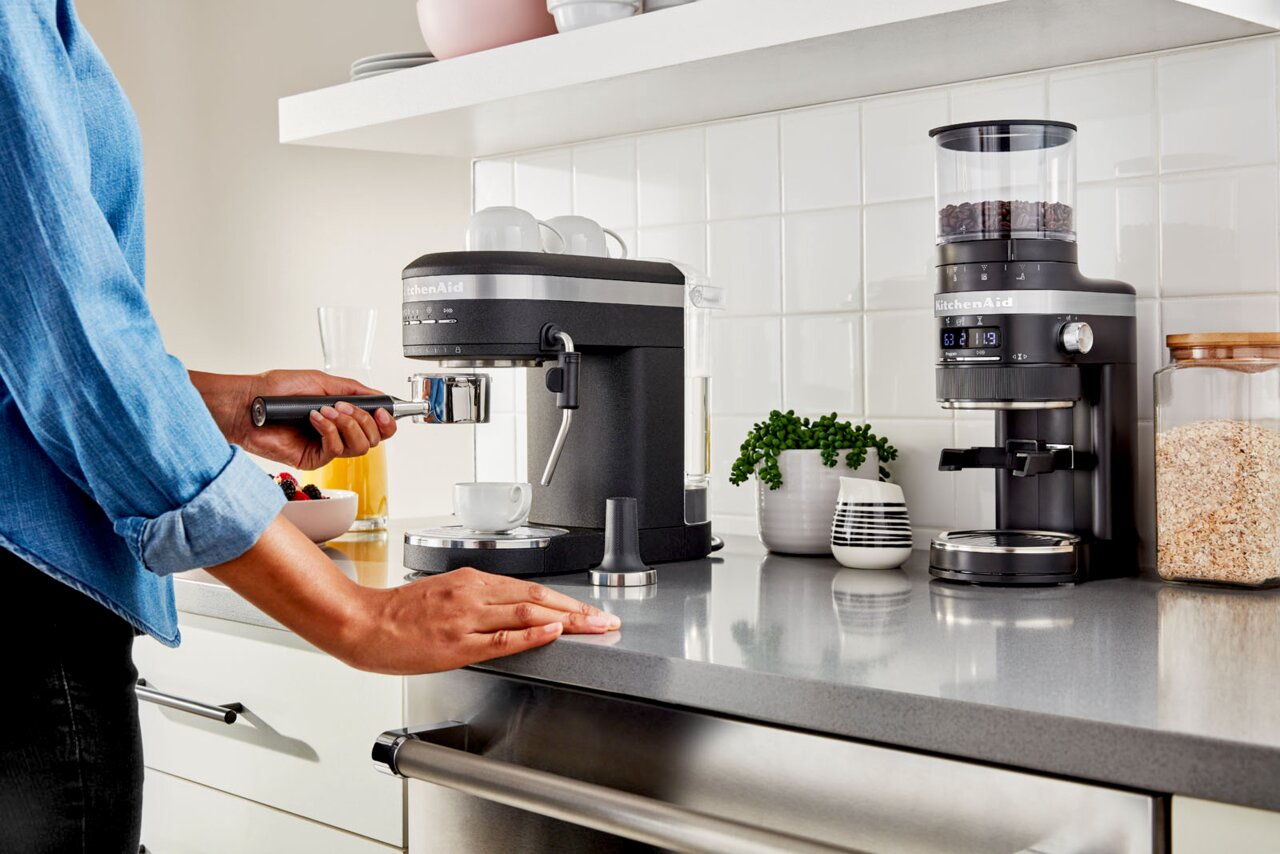 Küchenarbeitsplatte mit einer schwarzen Espressomaschine und Kaffeemühle, seitliche Perspektive