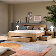 Modernes Holzbett in Eiche-Optik mit gepolstertem Kopfteil, integrierten Schubladen und Nachttischen im Schlafzimmer, gezeigt in frontaler leicht seitlicher Perspektive.
