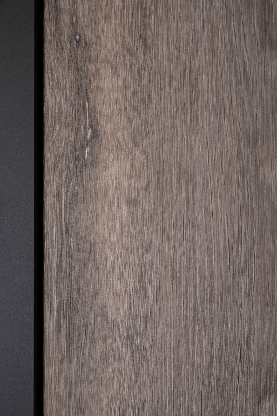 Nahaufnahme einer Holzoberfläche mit natürlicher Maserung und einem schwarzen Rand auf der linken Seite.