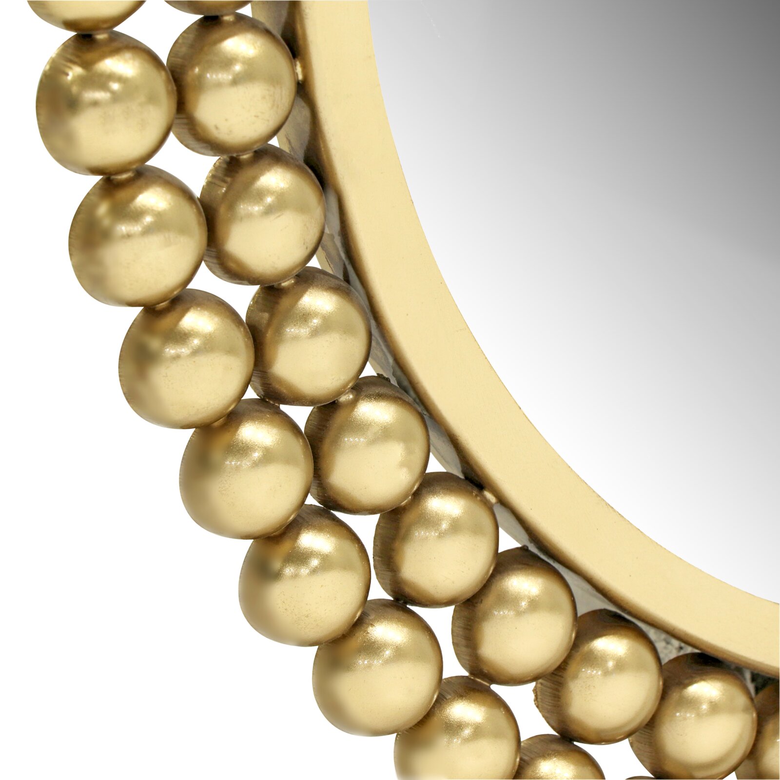 Close-up van een ronde spiegel met gouden bolletjes als versiering van de lijst, vanuit de zijkant in perspectief gefotografeerd.