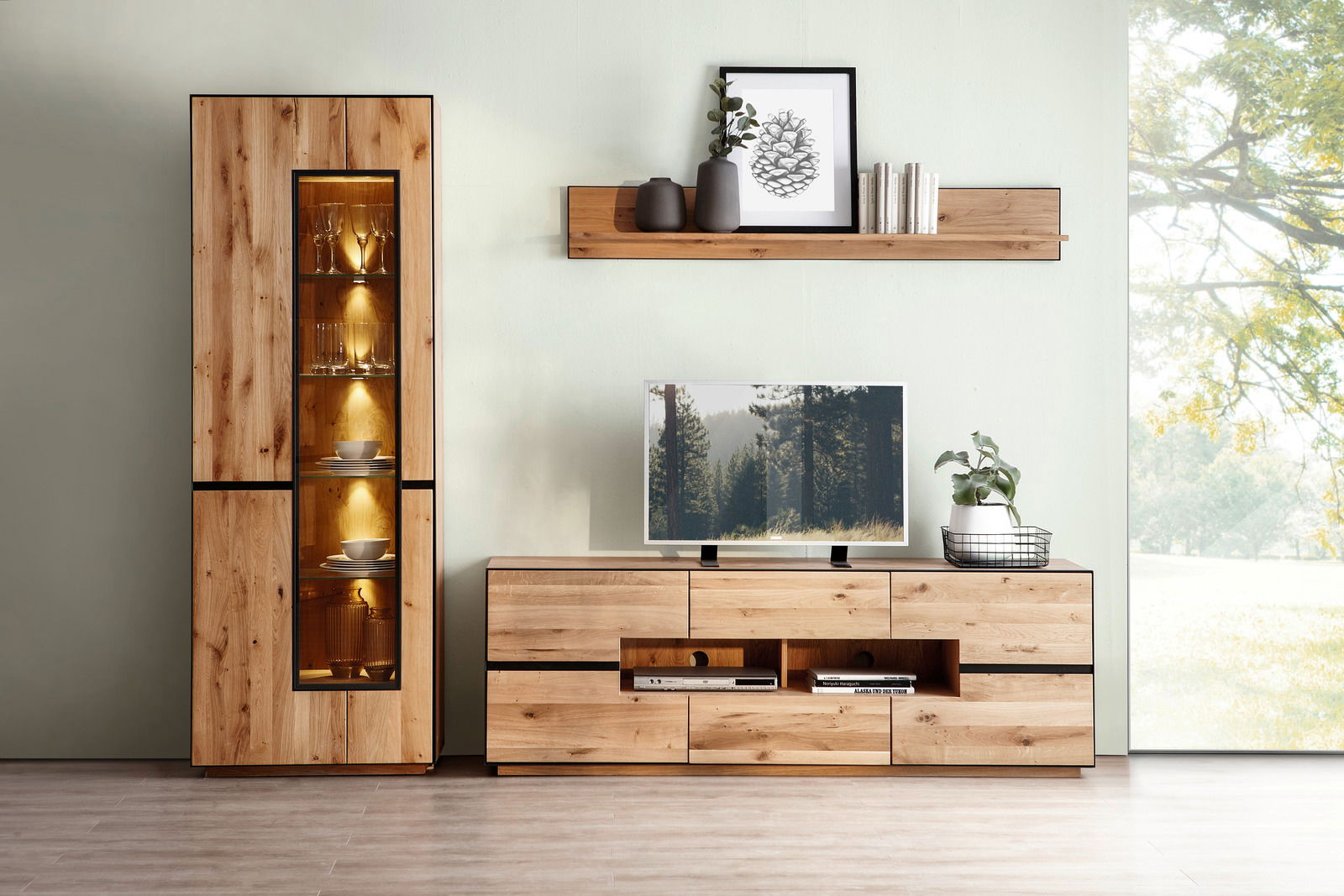Wohnzimmeransicht mit beleuchteter Vitrine, Wandboard und TV-Element aus Holz in moderner Einrichtung.