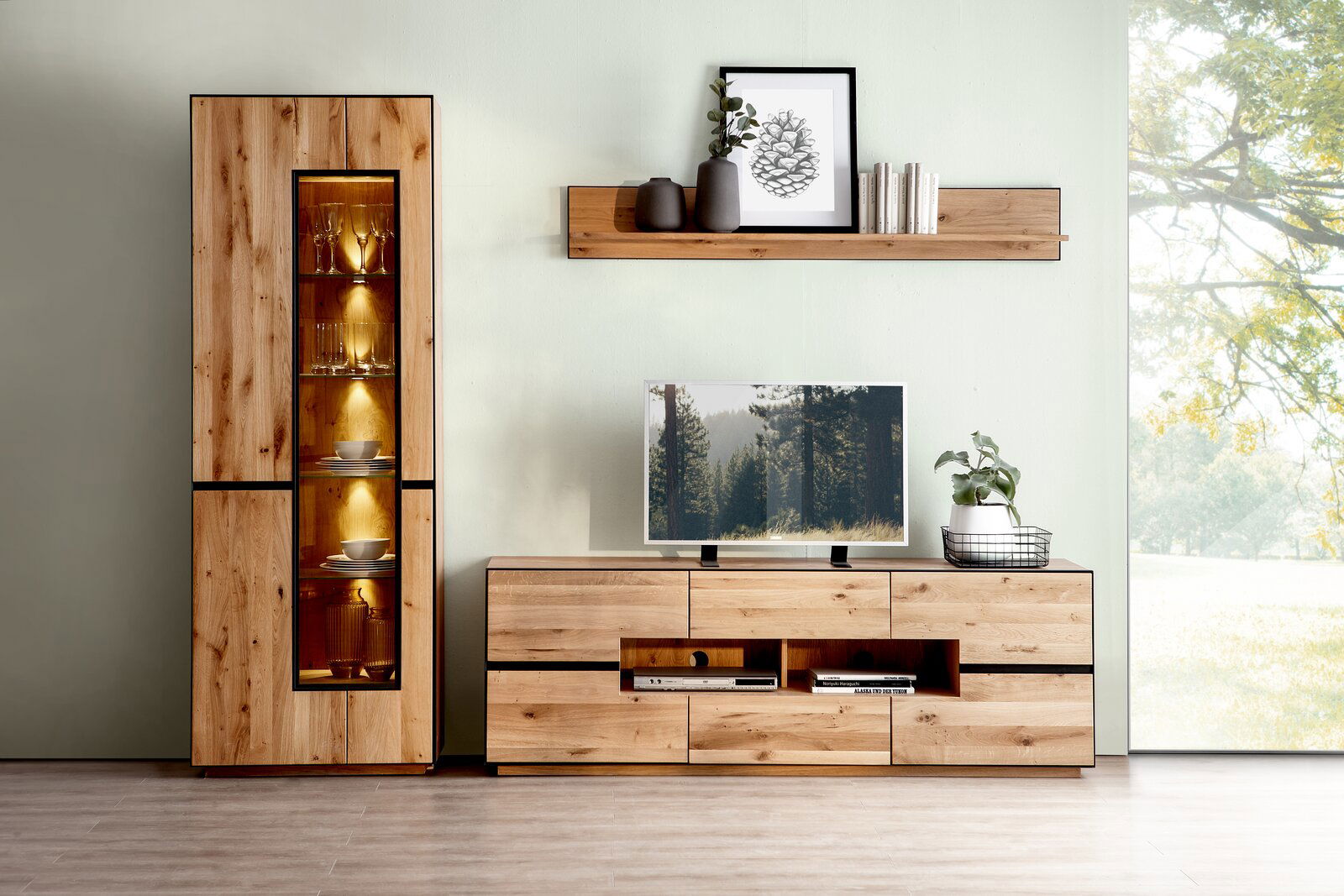 Wohnzimmeransicht mit beleuchteter Vitrine, Wandboard und TV-Element aus Holz in moderner Einrichtung.