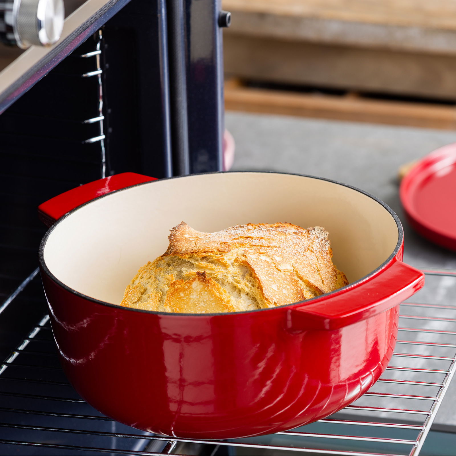 Roter ovaler Gusseisen-Bräter mit Brot im Ofen, seitliche Perspektive