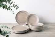 Tafelservice 8-tlg. in natürlichem Design mit sanften Beige- und Blautönen, bestehend aus flachen und tiefen Tellern, auf einem Holztisch arrangiert. Seitliche Perspektive.