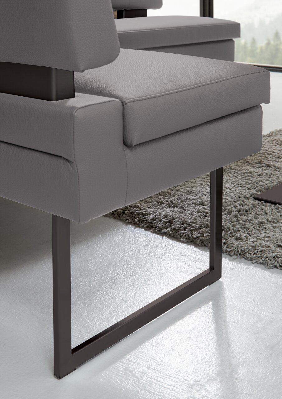 Detailansicht einer modernen grauen Eckbank mit Metallbeinen auf einem Teppichboden.
