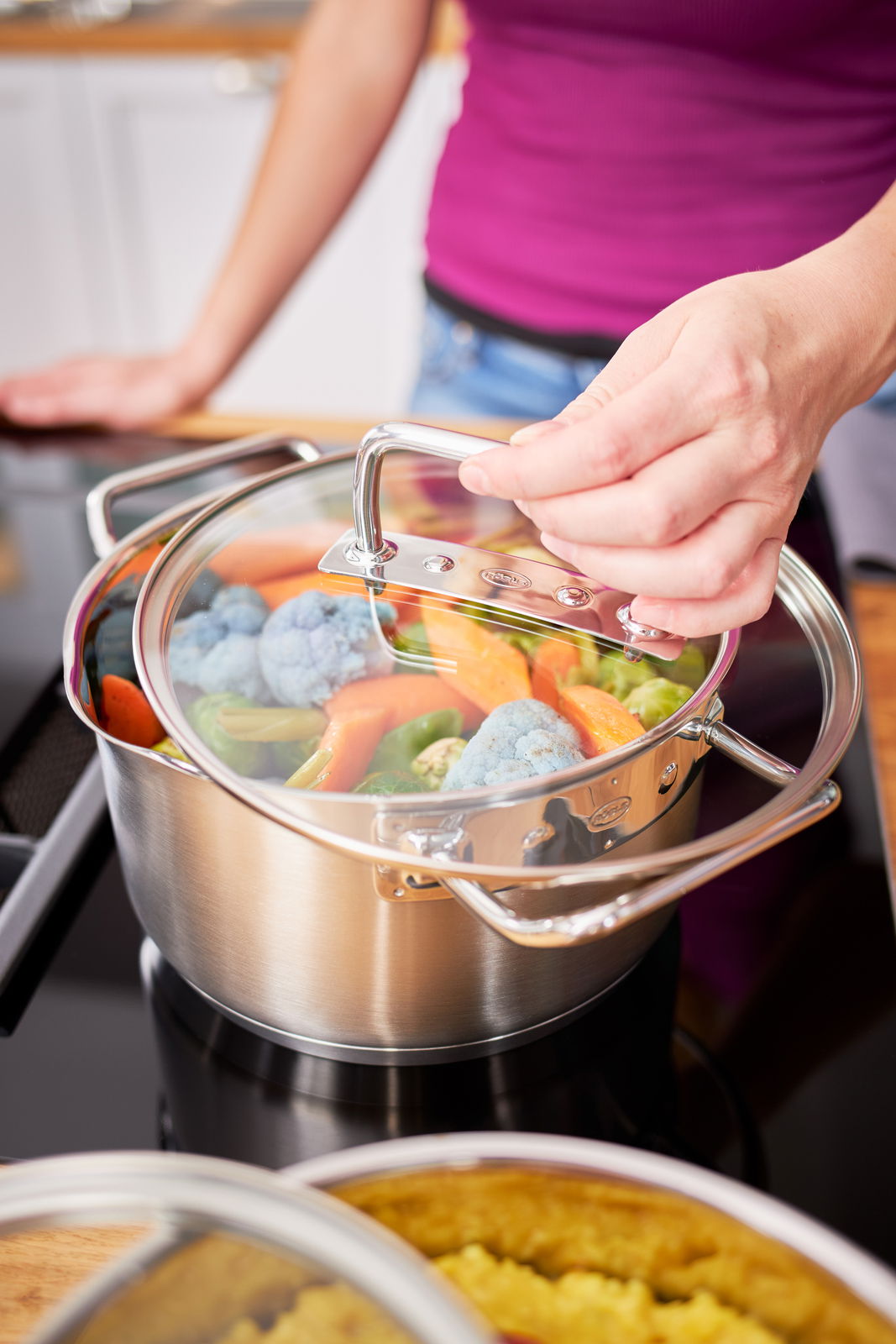 Rösle Kochtopf EXPERTISO Kochtopf Expertiso 24cm mit Glasdeckel, gefüllt mit Gemüse, auf einem Herd, aus der Perspektive von oben betrachtet.