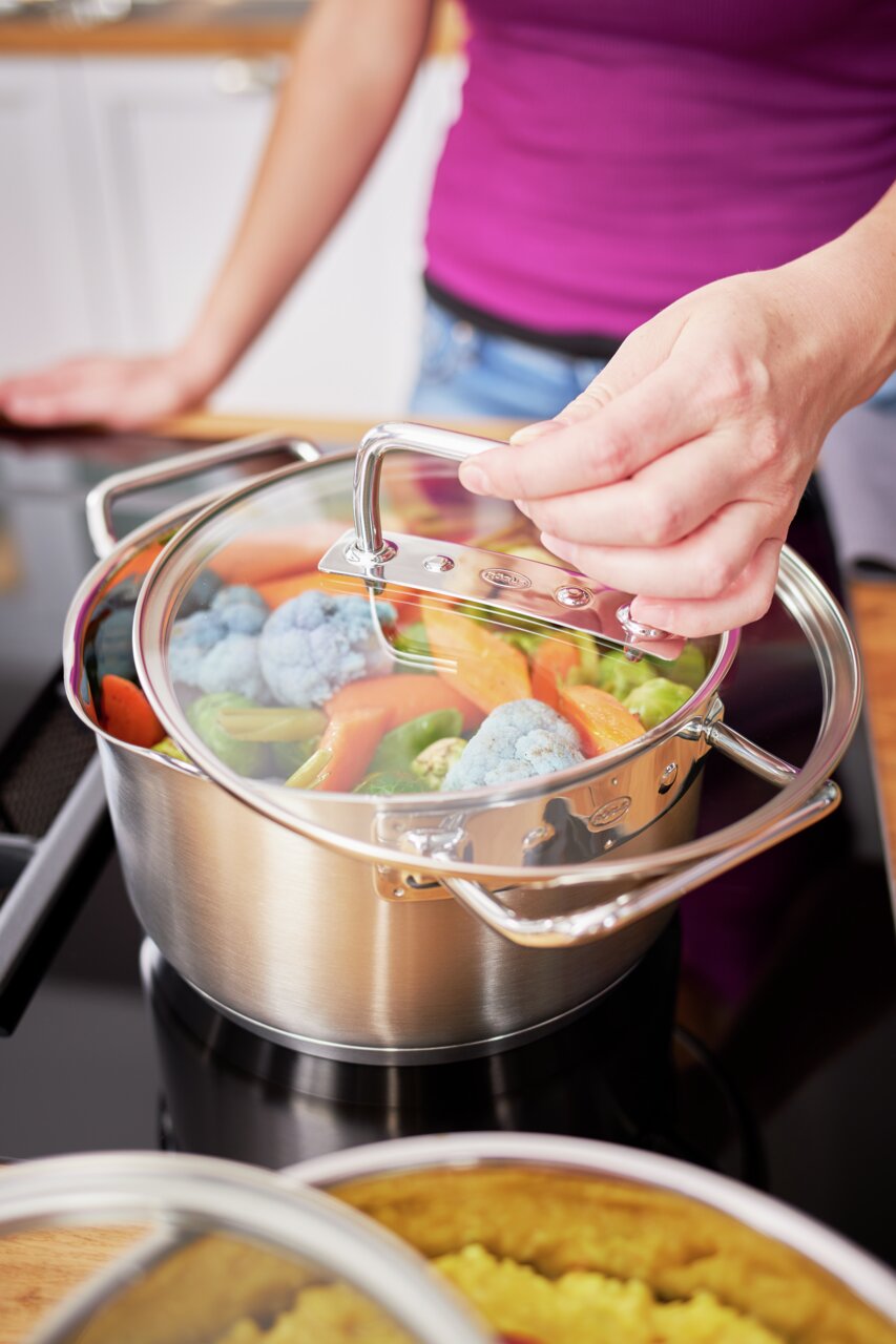 Rösle Kochtopf EXPERTISO Kochtopf Expertiso 24cm mit Glasdeckel, gefüllt mit Gemüse, auf einem Herd, aus der Perspektive von oben betrachtet.