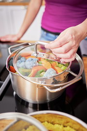 Kochtopf Expertiso 24cm mit Glasdeckel, gefüllt mit Gemüse, auf einem Herd, aus der Perspektive von oben betrachtet.