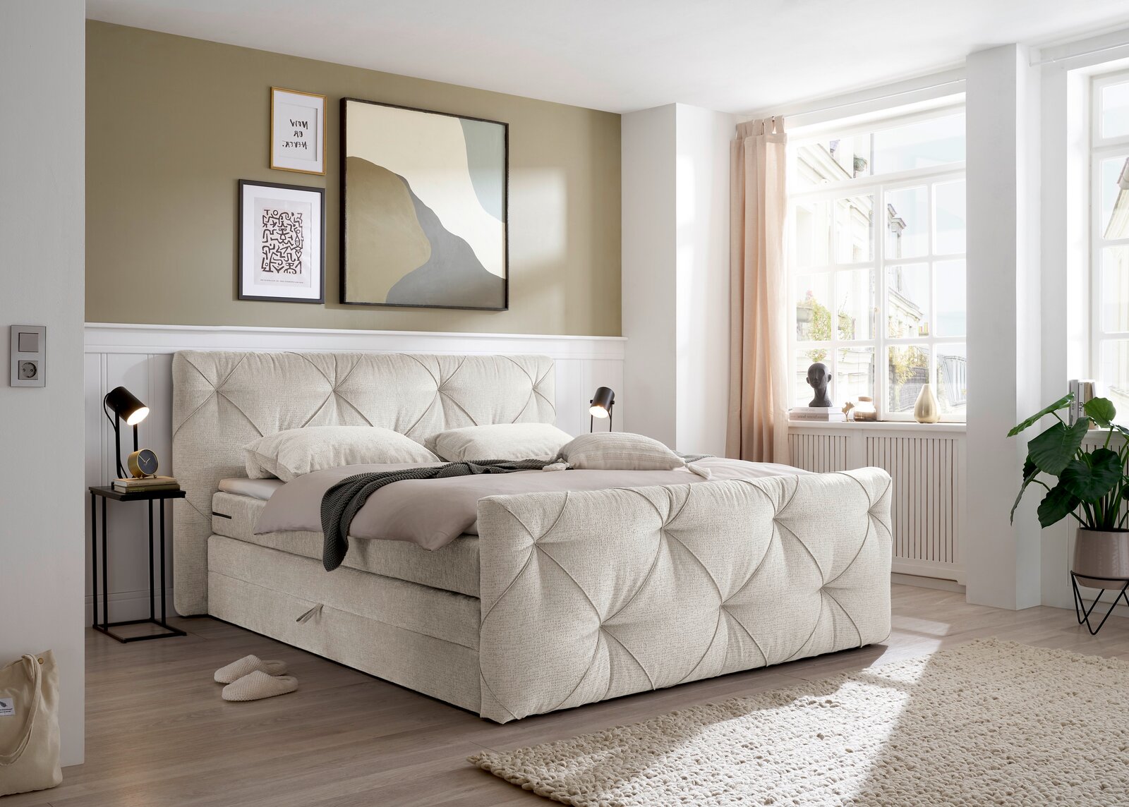 Boxspringbett in einem modernen Schlafzimmer, seitliche Perspektive mit Tageslicht durch ein großes Fenster.