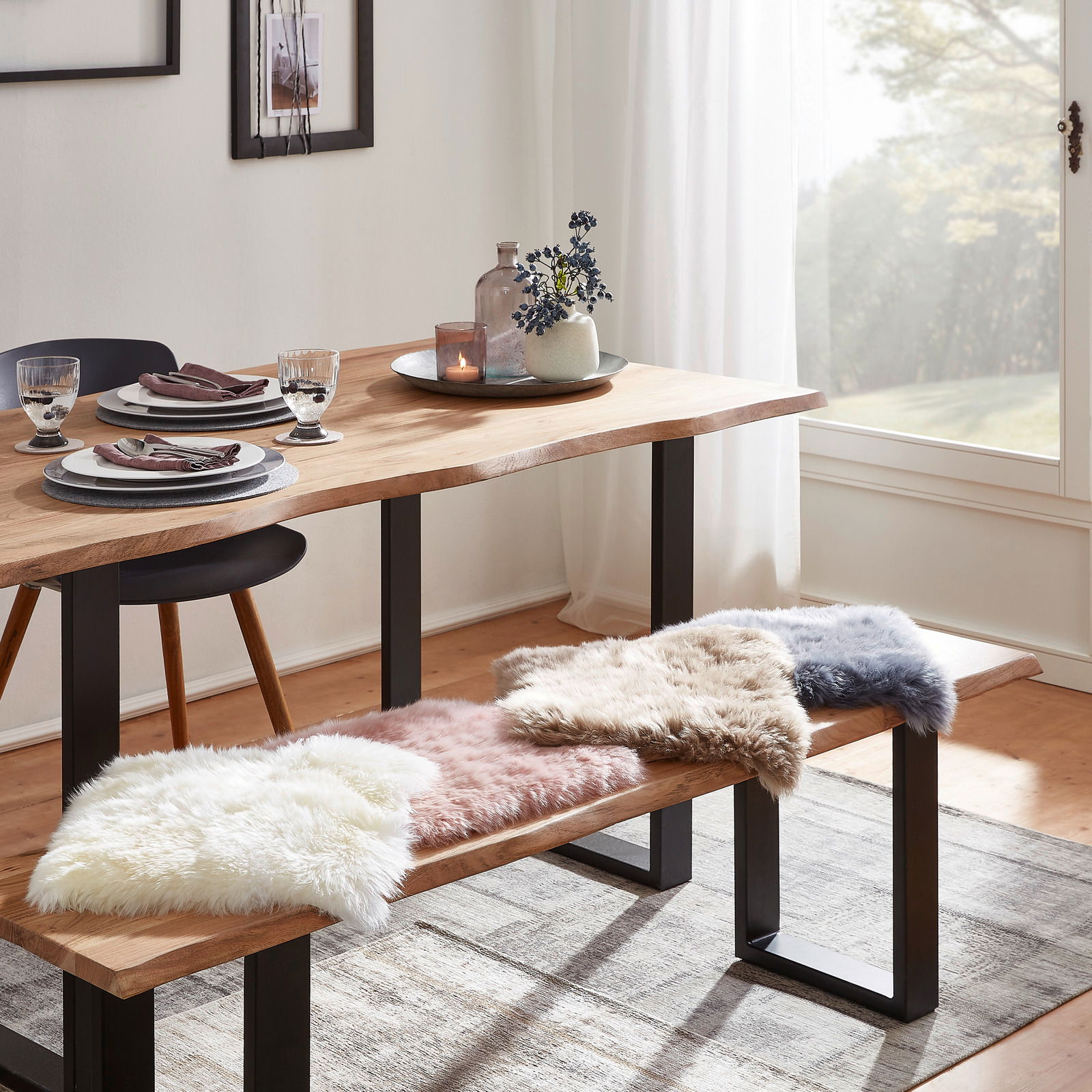 Zurbrüggen Lammfell Sitzauflage Esszimmer mit Holztisch und Bank, dekoriert mit Sitzkissen aus Schaffell in verschiedenen Farben, seitliche Perspektive