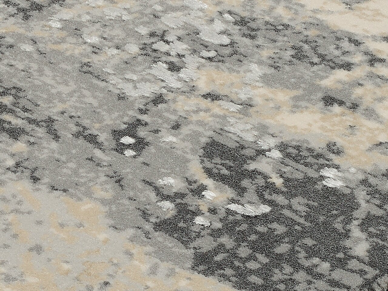 Nahaufnahme eines Designer Teppichs mit abstraktem Muster in Grau- und Beigetönen, von oben betrachtet.