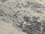 Nahaufnahme eines Designer Teppichs mit abstraktem Muster in Grau- und Beigetönen, von oben betrachtet.