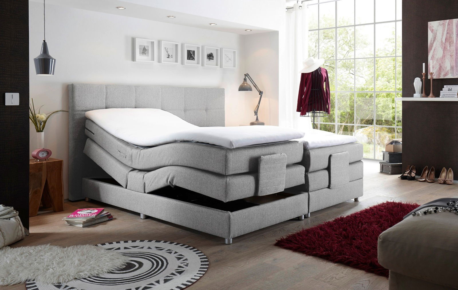 Graues Boxspringbett mit verstellbaren Matratzen in einem modernen Schlafzimmer, seitliche Perspektive.