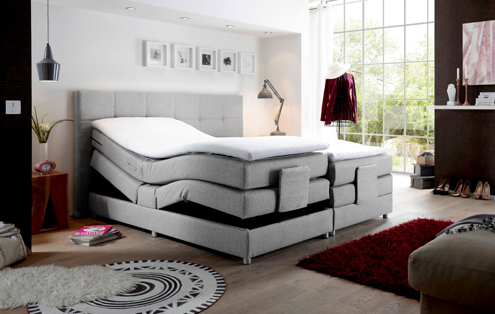 Graues Boxspringbett mit verstellbaren Matratzen in einem modernen Schlafzimmer, seitliche Perspektive.