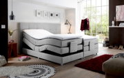 Graues Boxspringbett mit verstellbaren Matratzen in einem modernen Schlafzimmer, seitliche Perspektive.