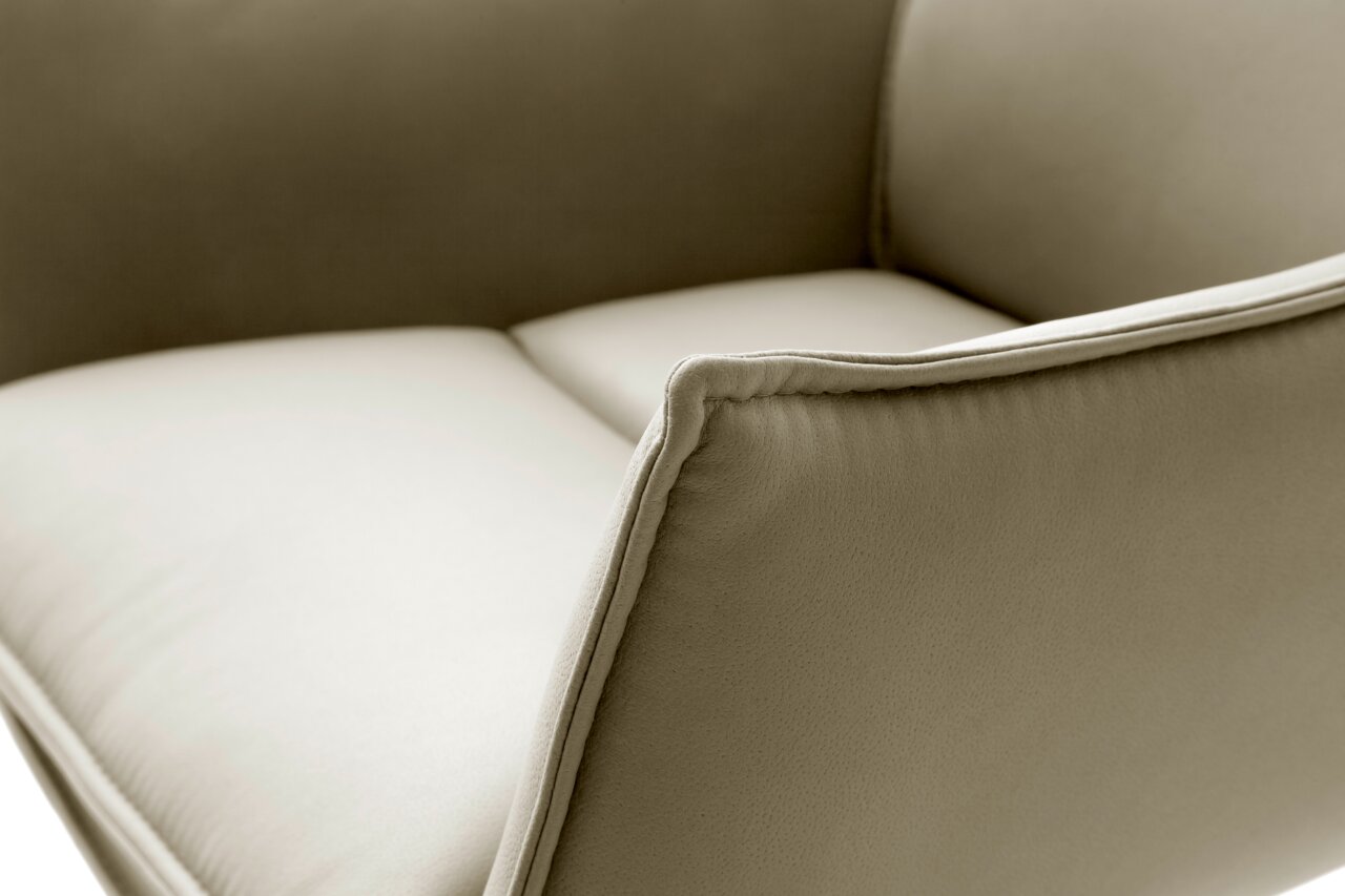 Nahaufnahme eines Sessels mit beigem Stoffbezug, seitliche Perspektive