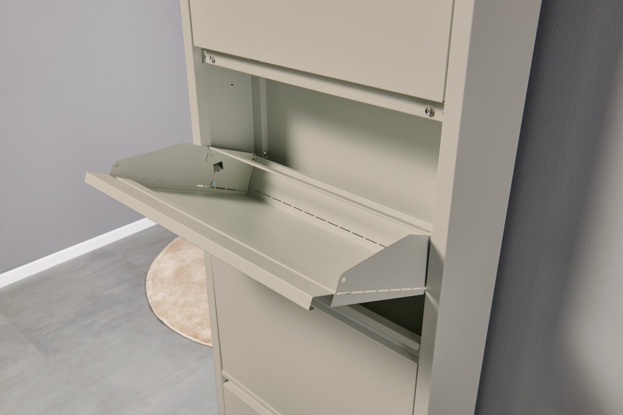 Geöffnete, nach vorn abklappende Metallklappe eines hellgrauen Schrank-/Gehäusemoduls, Detailansicht aus schräger Seitenperspektive von vorn