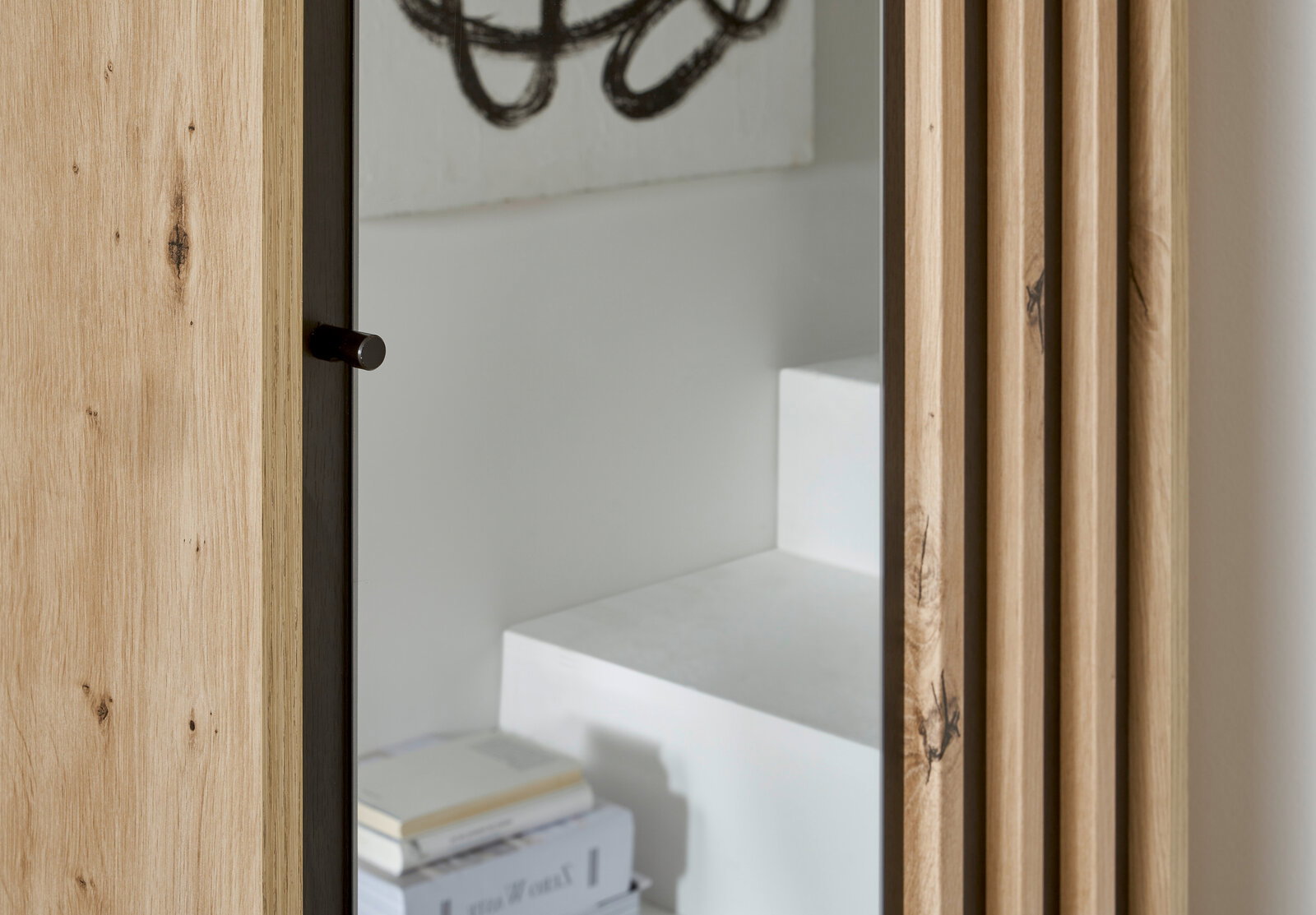 Nahaufnahme eines Garderobenschranks mit Holzmaserung und Spiegel, seitliche Perspektive.