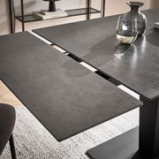 Moderner Esstisch mit erweiterbarer Tischplatte in dunkler Steinoptik, seitliche Perspektive.
