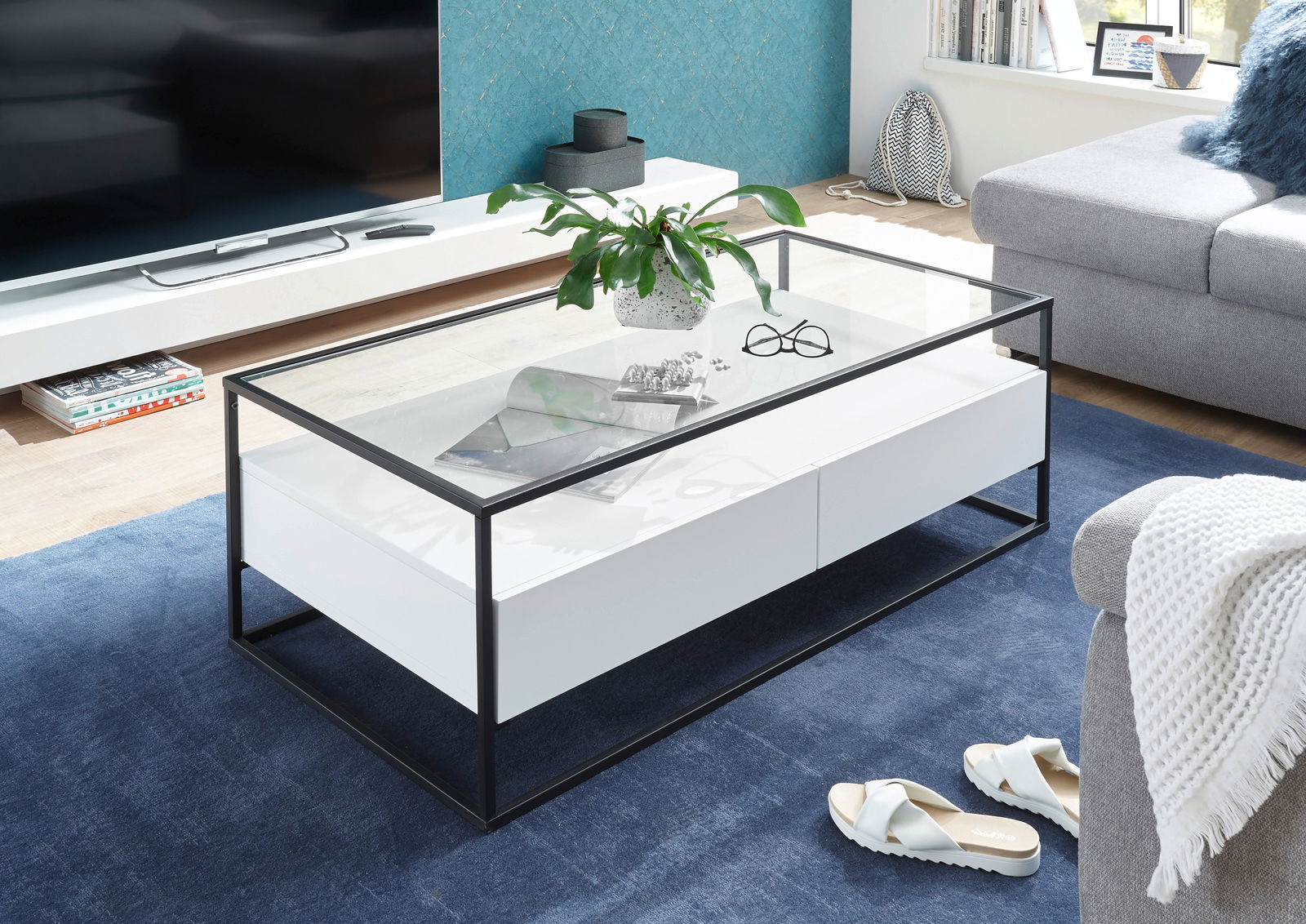 Moderner Couchtisch mit Glasplatte und schwarzem Metallrahmen, seitliche Perspektive
