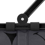 Nahaufnahme des oberen Teils eines grauen Reisenthel carrybag mit schwarzem Griff und Logo, von vorne betrachtet.