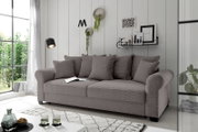 Graues Funktionssofa mit mehreren Kissen, seitliche Perspektive, in einem modernen Wohnzimmer mit großen Fenstern und dekorativen Elementen an der Wand.