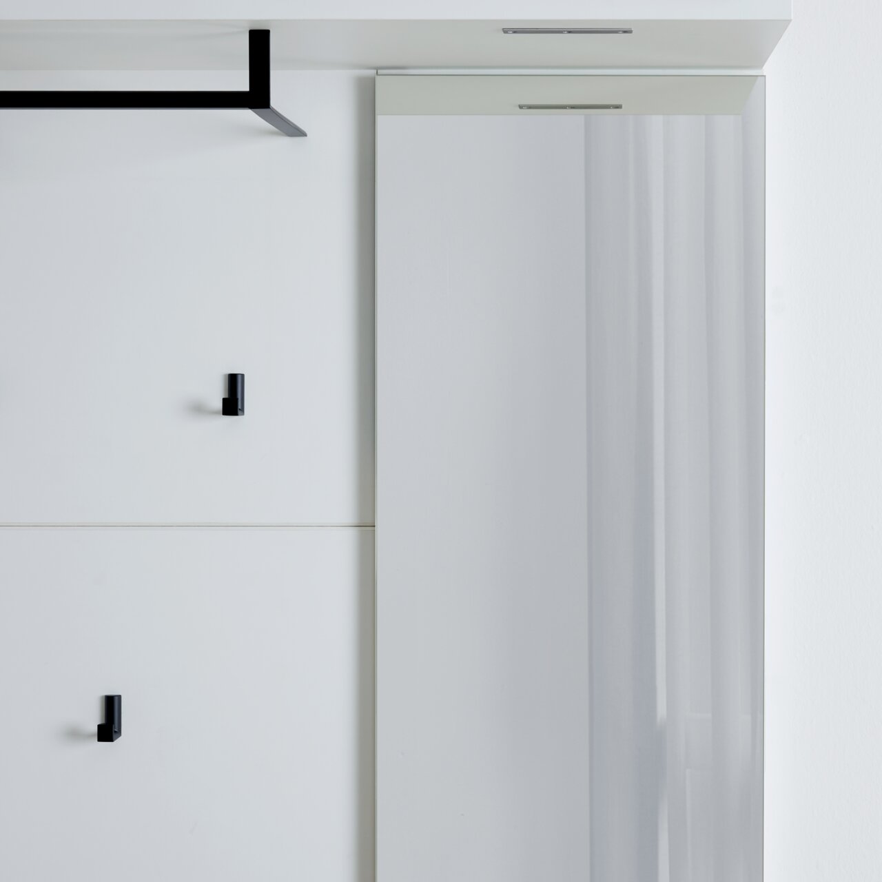 Modernes Garderobenpaneel mit schwarzem Haken und Spiegel, seitliche Perspektive