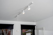 Deckenstrahler FAVORI in Weiß, montiert an einer Schiene an der Decke, Perspektive von unten.