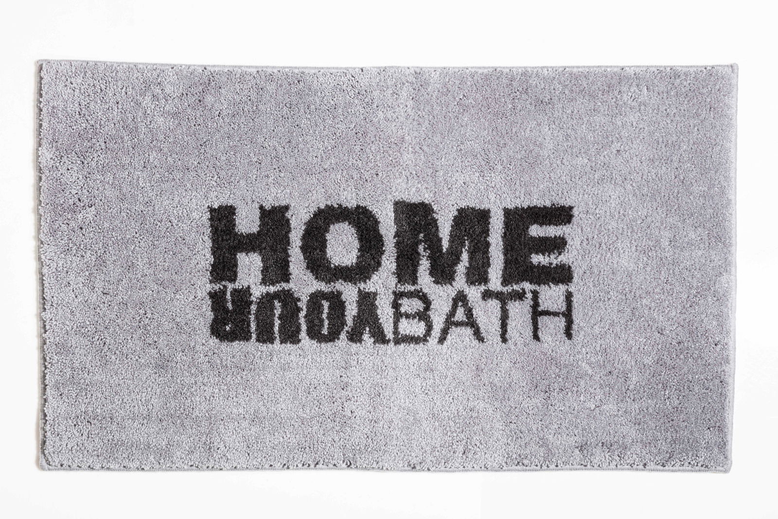 Grauer Badteppich mit schwarzem Schriftzug 'HOME YOUR BATH', von oben betrachtet.