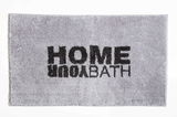 Grauer Badteppich mit schwarzem Schriftzug 'HOME YOUR BATH', von oben betrachtet.