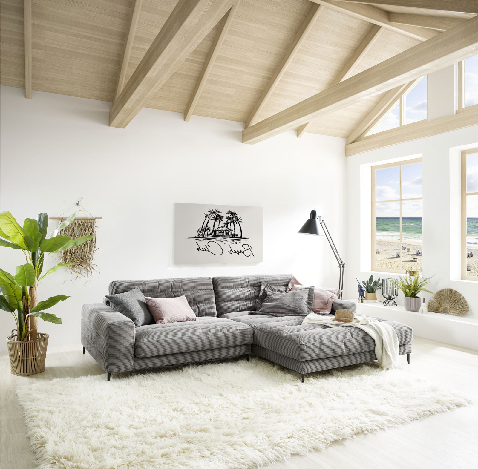 Graue Longchairkombination in einem hellen Wohnzimmer mit großen Fenstern und Blick auf den Strand, aus der Perspektive von vorne links.