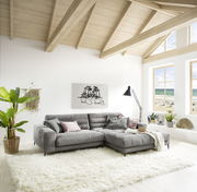 Graue Longchairkombination in einem hellen Wohnzimmer mit großen Fenstern und Blick auf den Strand, aus der Perspektive von vorne links.