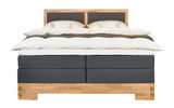 Frontale Ansicht eines stilvollen Boxspringbetts mit Holzrahmen und dunklem Stoffbezug, ausgestattet mit bequemer Bettwäsche und Kissen.