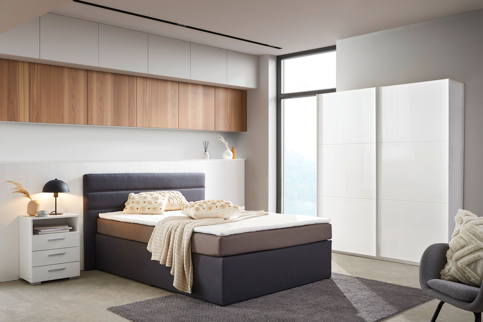 Moderner, weißer Schwebetürenschrank mit zwei Türen in einem stilvoll eingerichteten Schlafzimmer, seitliche Perspektive.