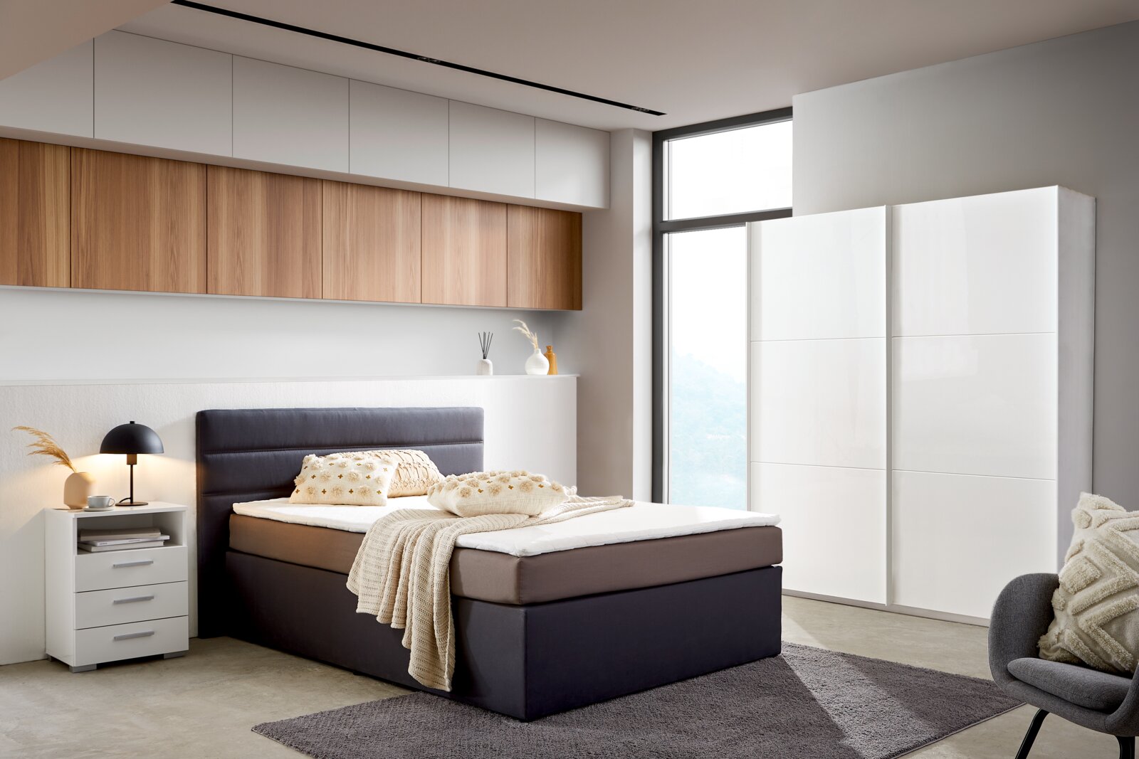 Moderner, weißer Schwebetürenschrank mit zwei Türen in einem stilvoll eingerichteten Schlafzimmer, seitliche Perspektive.