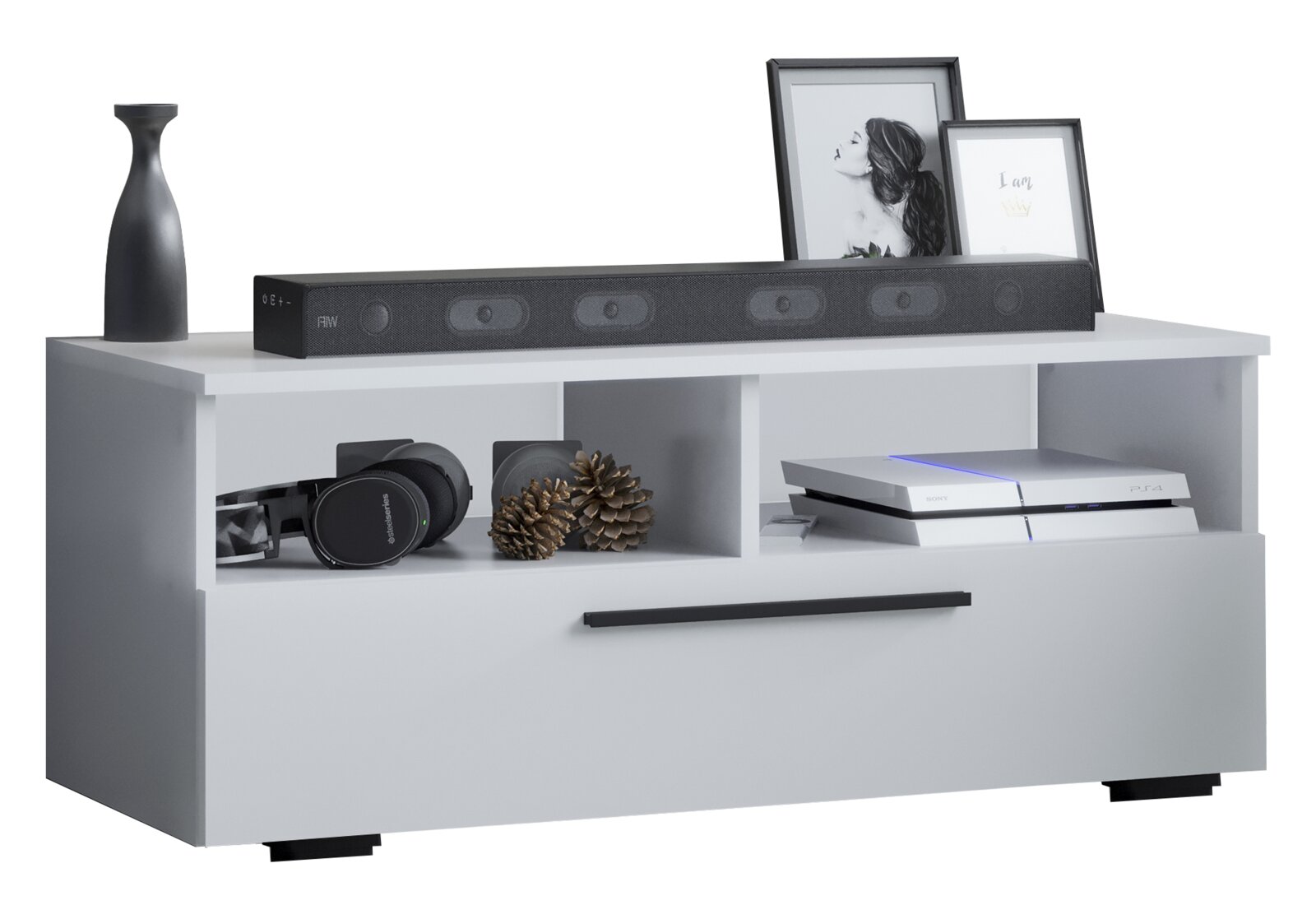 Weißes TV-Lowboard mit zwei offenen Fächern und großer Schublade mit schwarzem Griff, dekoriert mit Soundbar, Vase und Bilderrahmen; Ansicht schräg von vorne.
