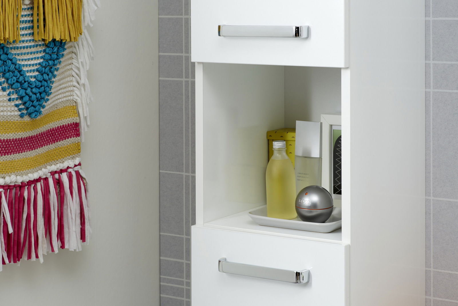 XORA Hochschrank TIVOLI Hochschrank mit zwei Schubladen und einem offenen Fach, gefüllt mit Pflegeprodukten, aus seitlicher Perspektive.