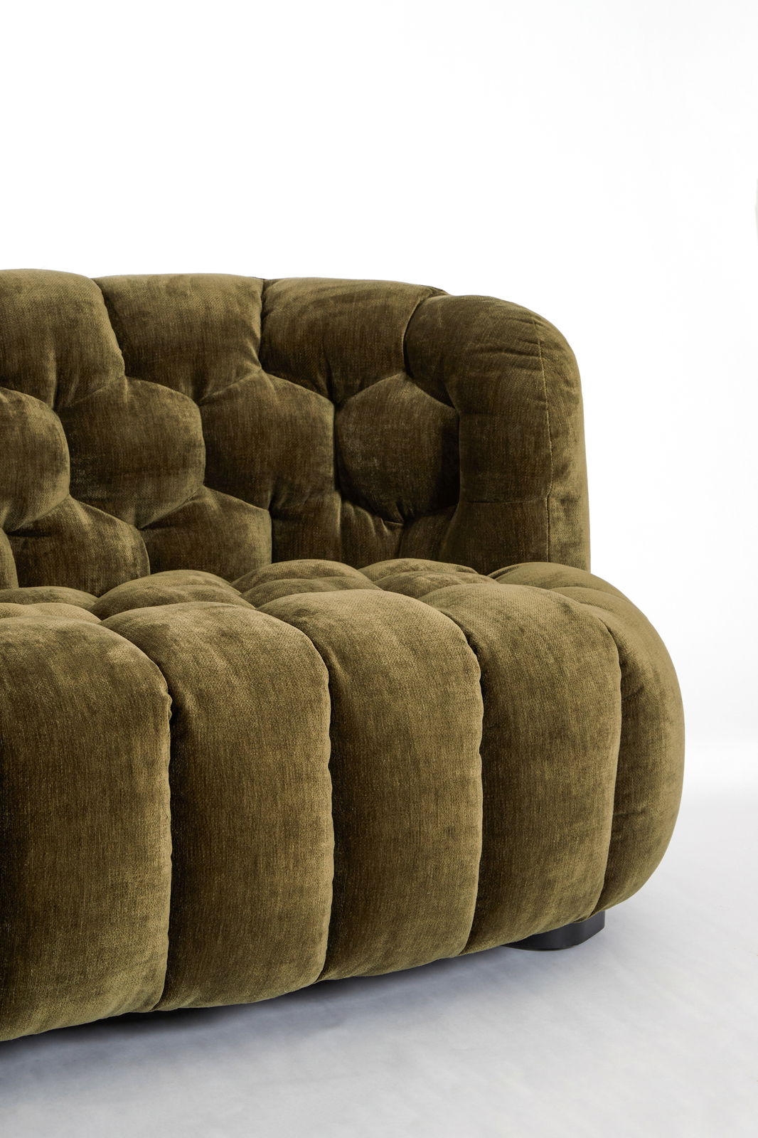 Detailansicht einer olivgrünen Couch mit gepolstertem, gestepptem Design.