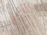 Nahaufnahme eines Designer-Teppichs mit abstraktem Muster in neutralen Tönen, perspektivisch von der Seite aufgenommen.