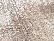 Nahaufnahme eines Designer-Teppichs mit abstraktem Muster in neutralen Tönen, perspektivisch von der Seite aufgenommen.