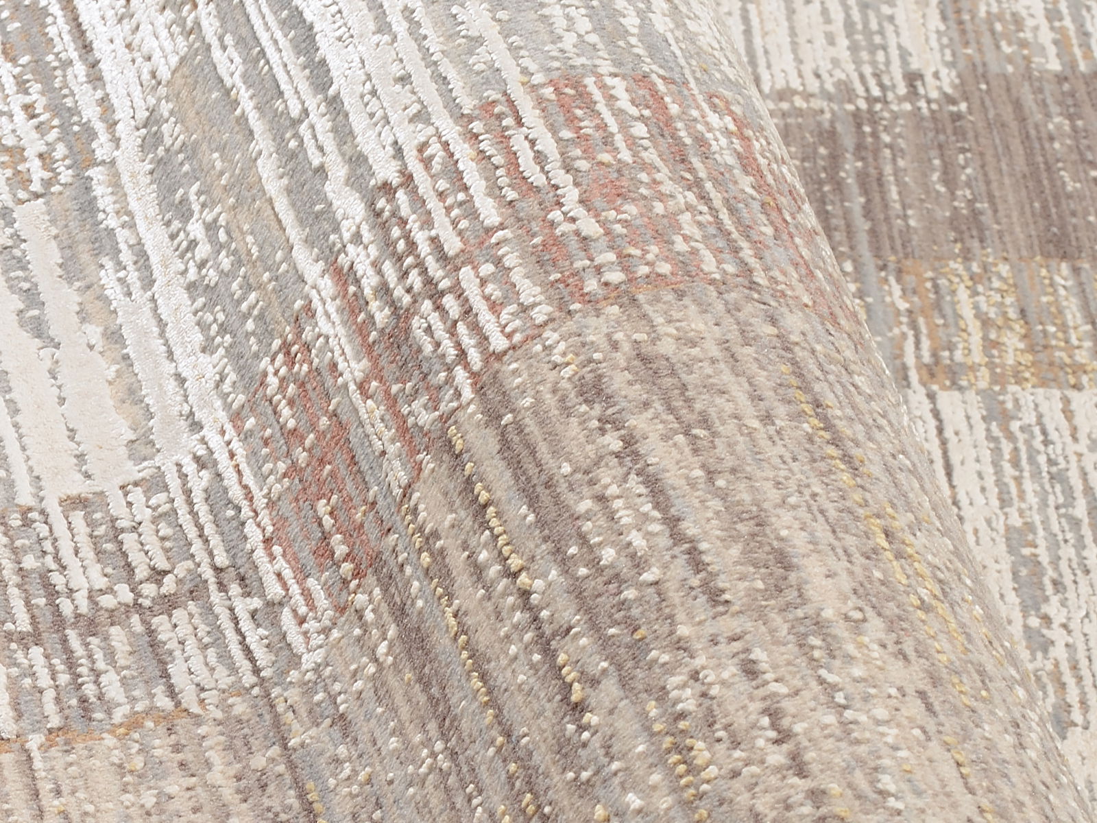 Nahaufnahme eines Designer-Teppichs mit abstraktem Muster in neutralen Tönen, perspektivisch von der Seite aufgenommen.