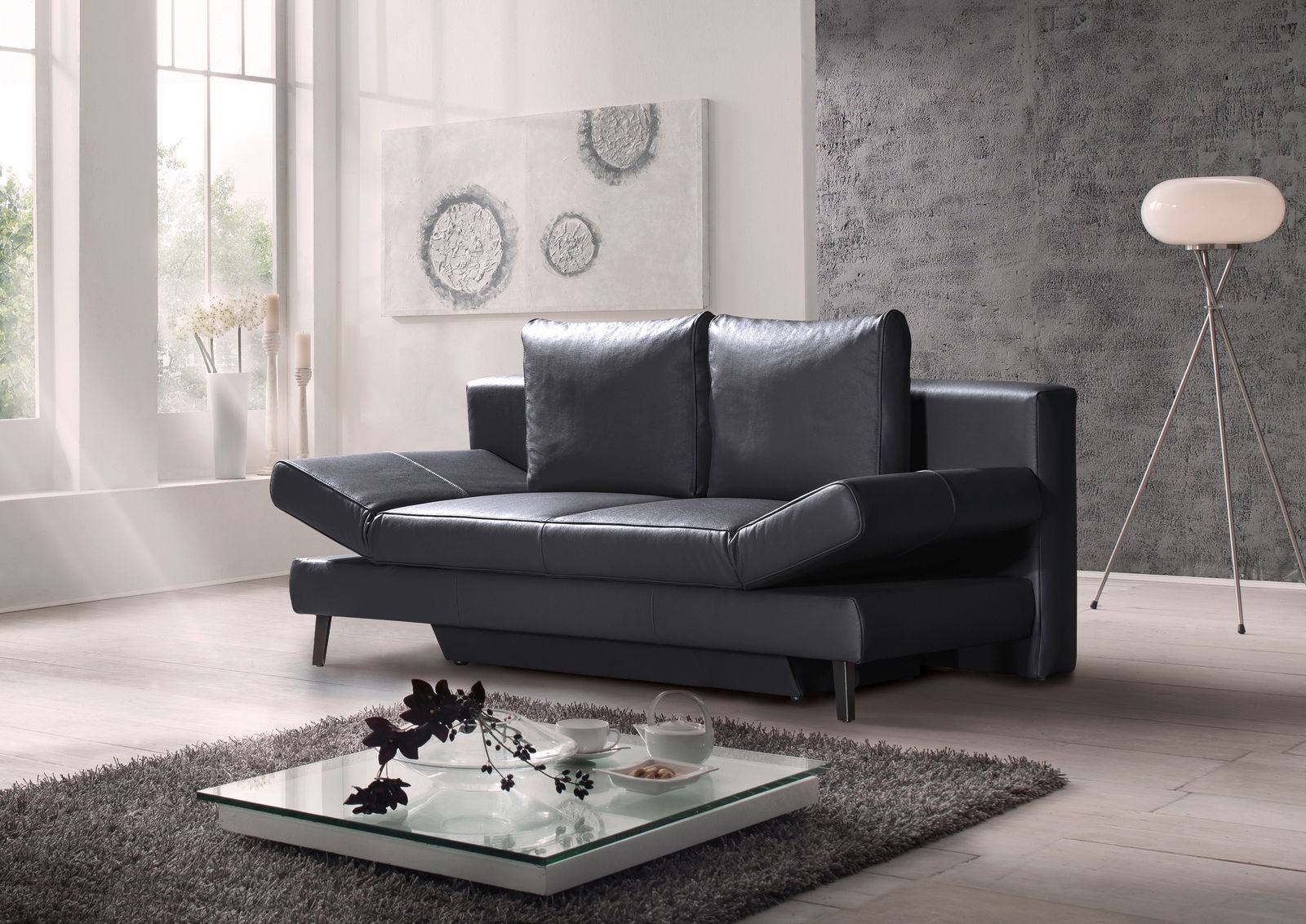 Schwarzes Querschläfer-Sofa in modernem Wohnzimmer, seitliche Perspektive