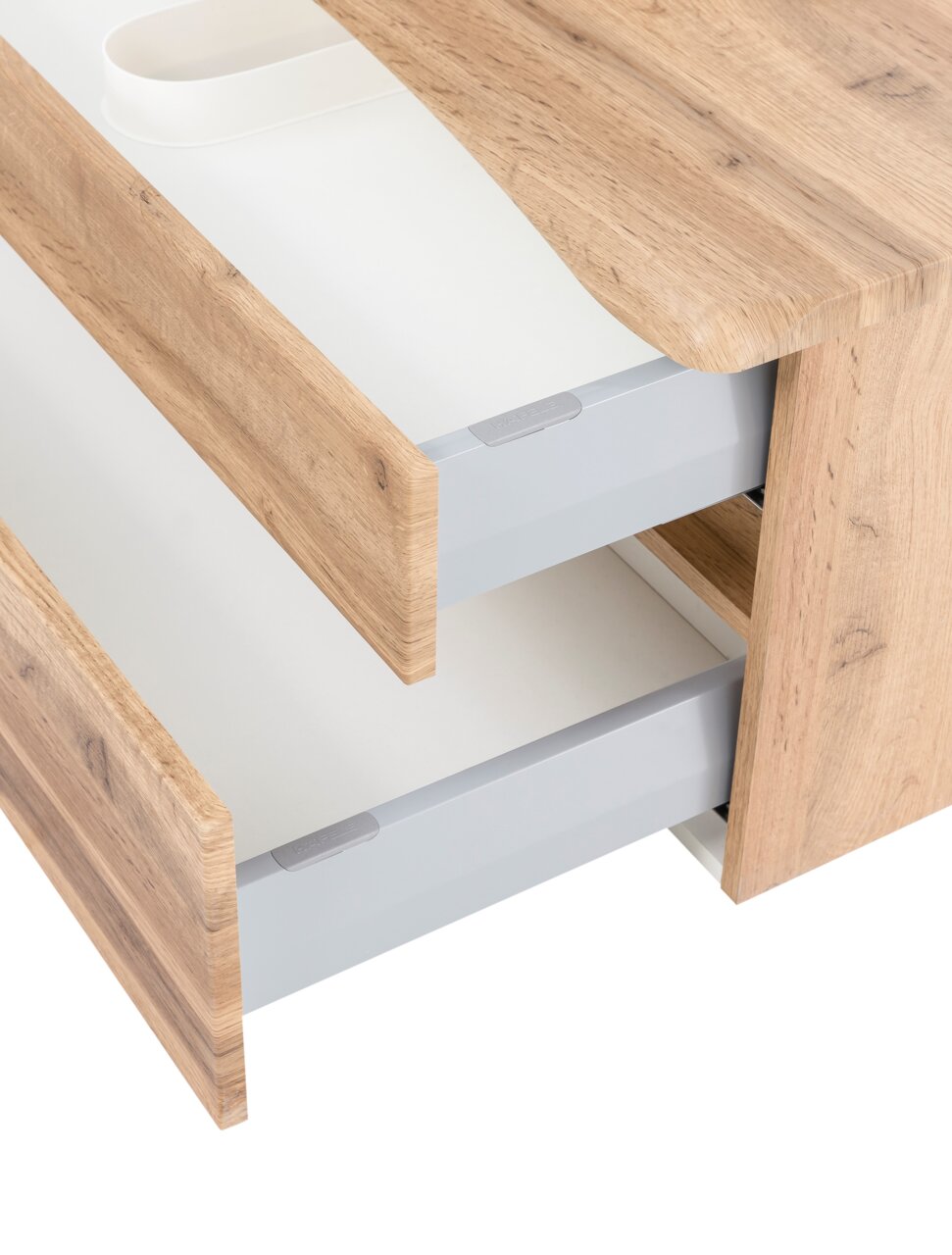 Close-up van een wastafelmeubel met twee open lades in houtlook, gezien vanaf de zijkant.
