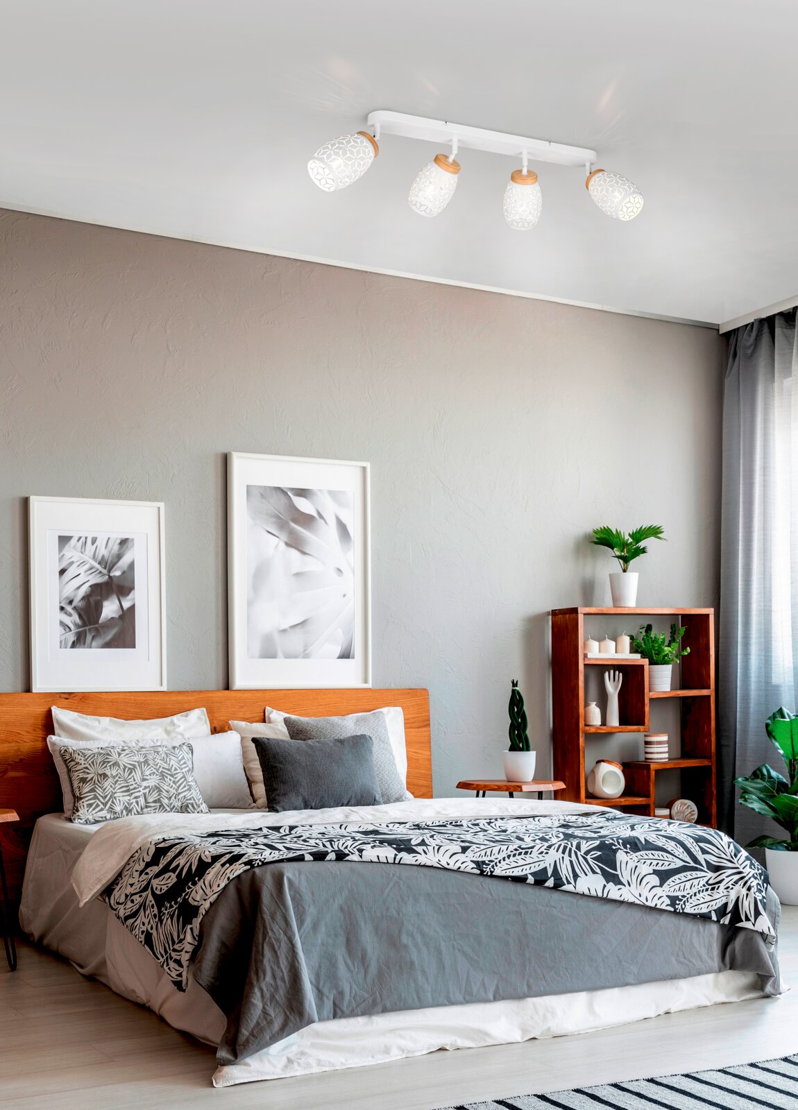 Plafondspots met vier witte lampenkappen met patronen in een moderne slaapkamer, gezien van onderaf.